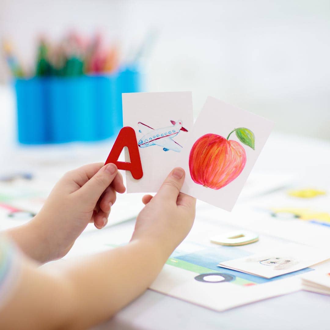 Kinderhände halten eine Zeichnung von einem Apfel